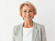 Frau in grauem Blazer, neutraler Hintergrund.